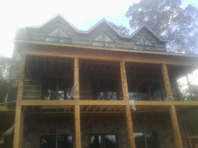 Dormers and porch framing on a large log home under construction — Roof Coating work by our crew in Jewell