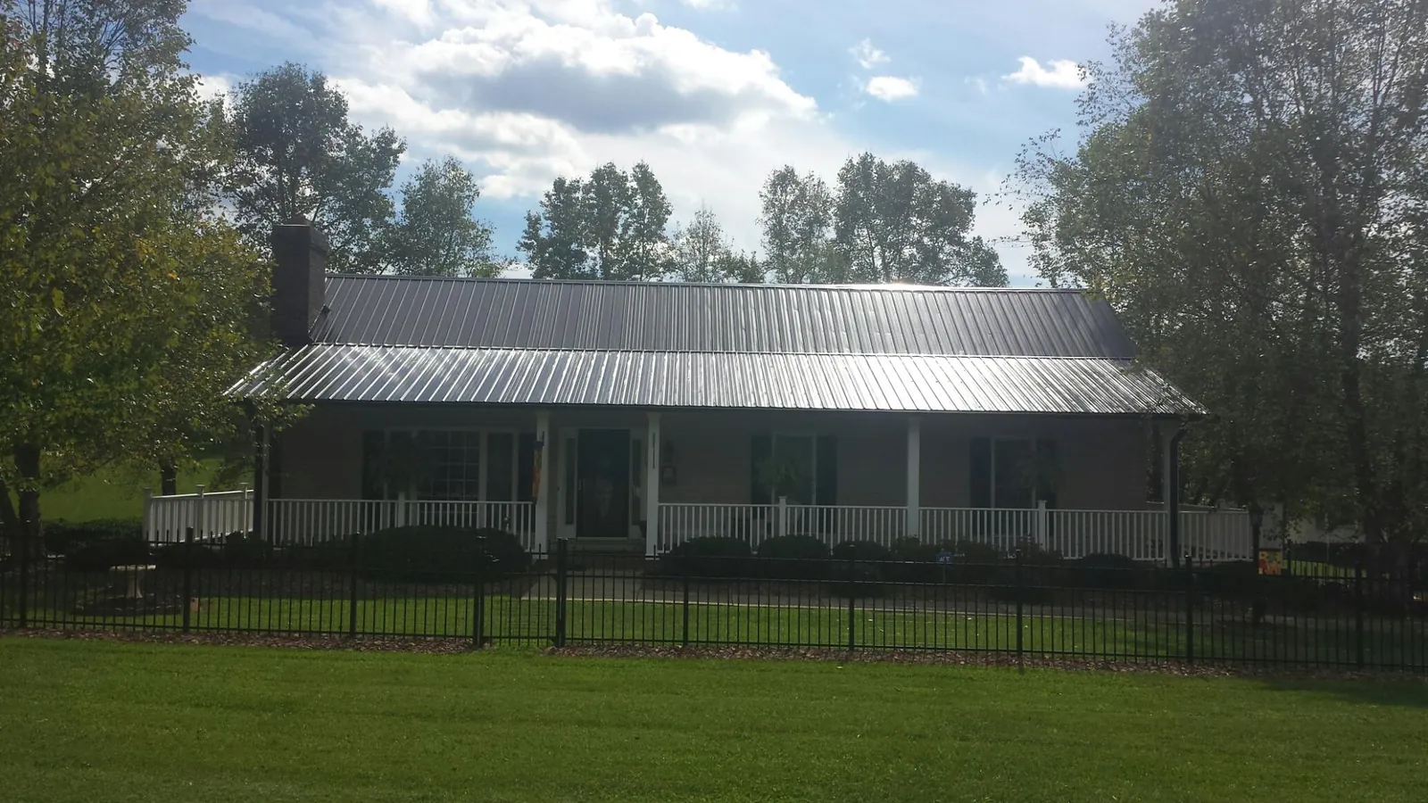 Gray metal roof on a brick ranch with a full width front porch — Gutter Guard Installation work by our crew in Jewell